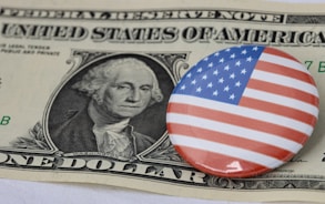 a one dollar bill and a button with a picture of george washington on it