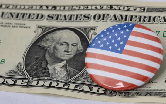 a one dollar bill and a button with a picture of george washington on it