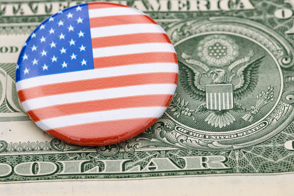 um botão com a bandeira americana em cima de uma nota de dólar
