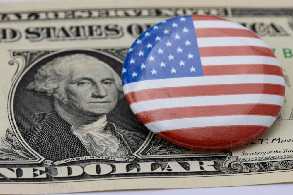 a button with the american flag on it sitting on top of a hundred dollar bill