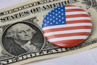 a button with the american flag on it sitting on top of a one dollar bill