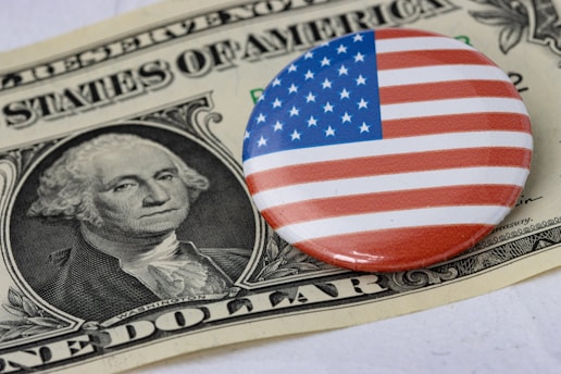 a button with the american flag on it sitting on top of a one dollar bill