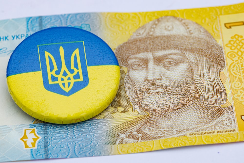 Un botón azul y amarillo sentado encima de un billete de dinero
