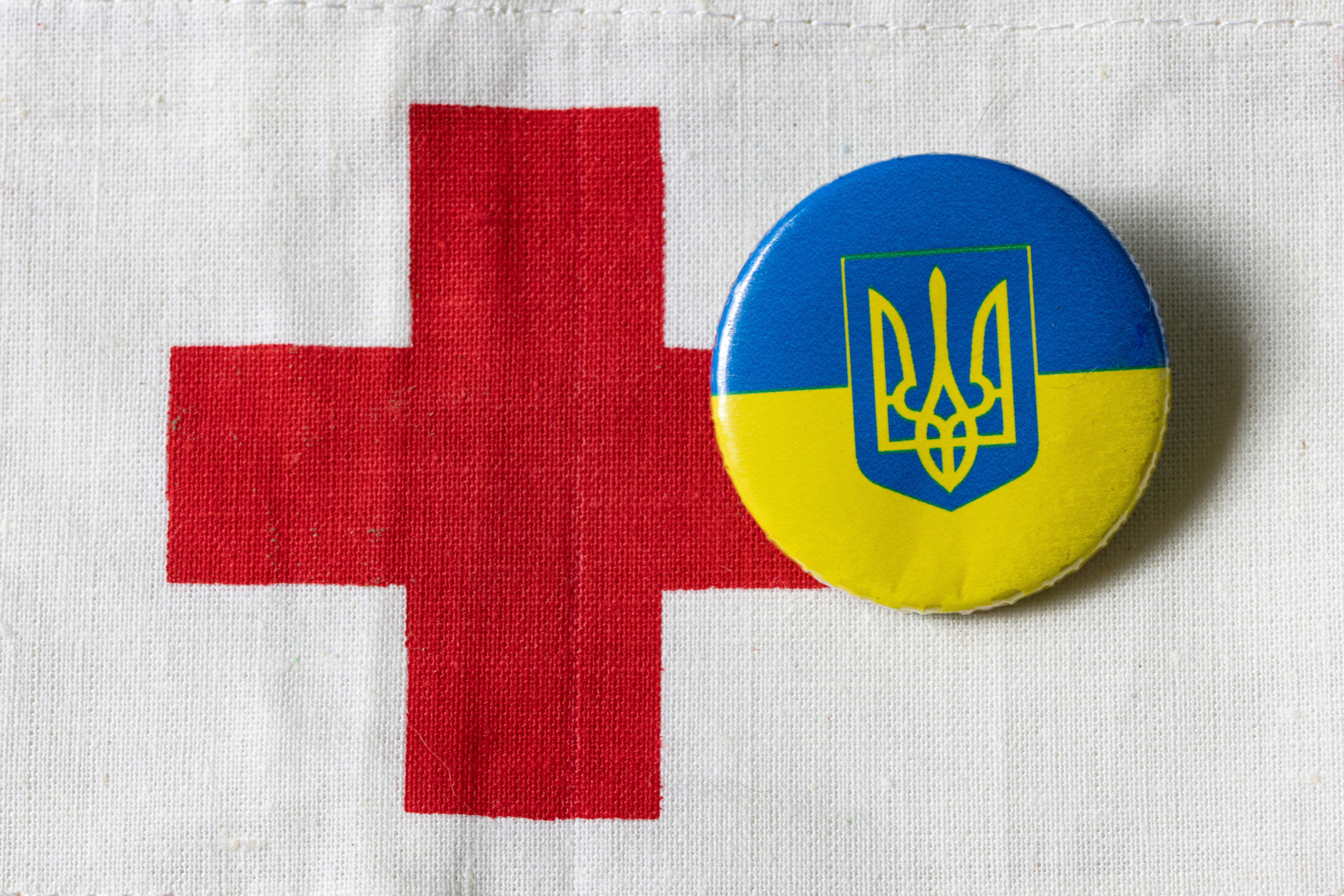 a button with the flag of ukraine and a red cross
