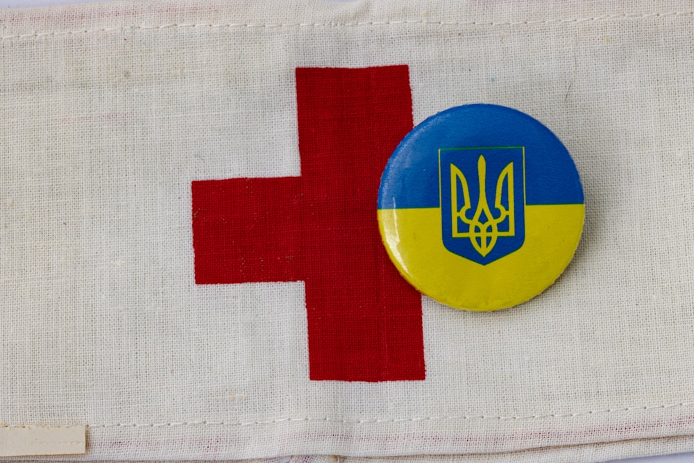 Ein Knopf mit einer Flagge des Landes Ukraine und einem roten Kreuz