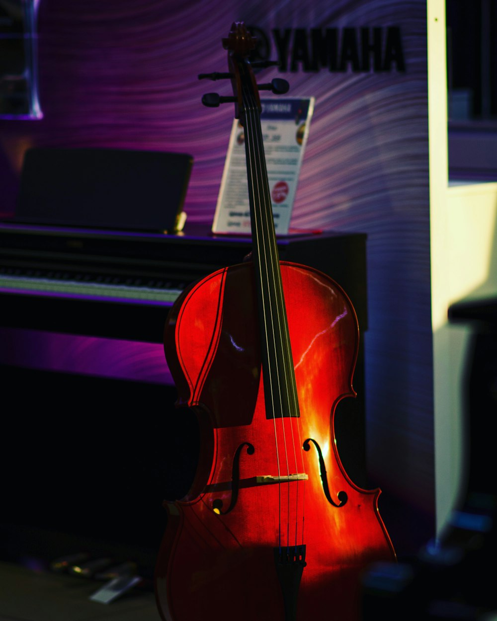 a red cello sitting in front of a piano