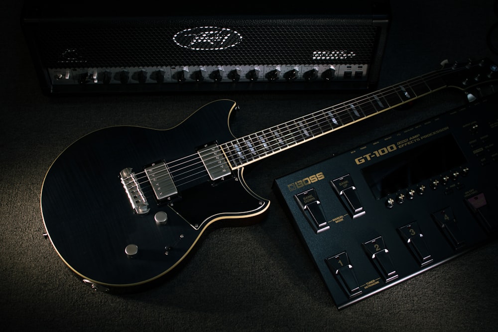 a black guitar sitting next to a amplifier