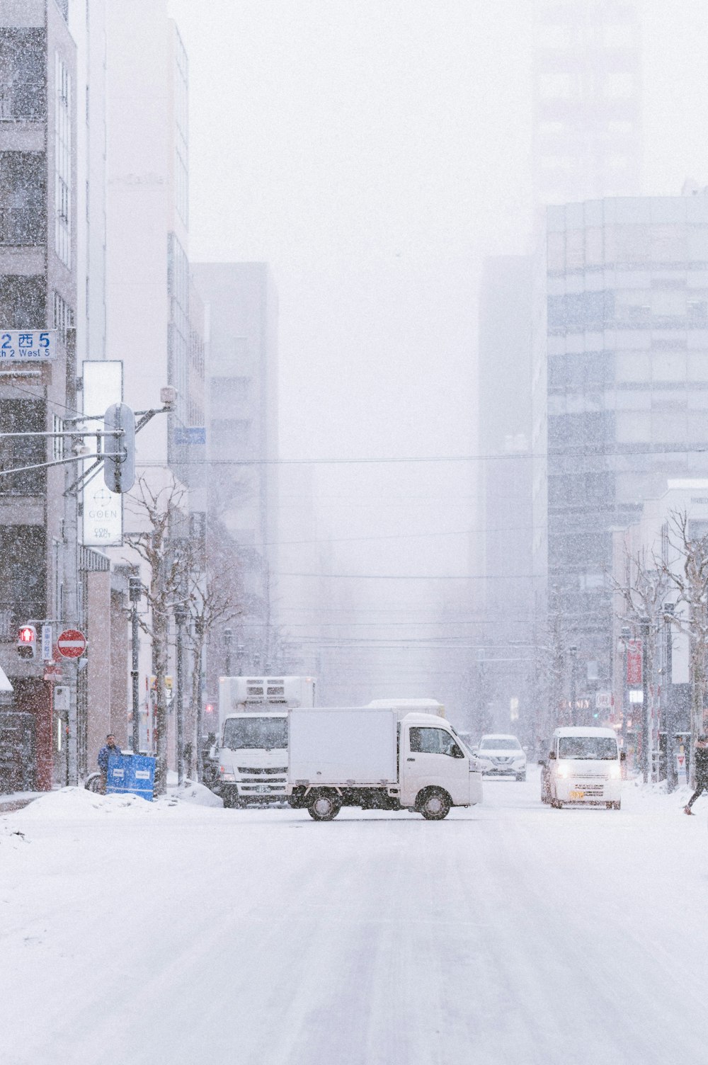 a snowy city street with cars and trucks