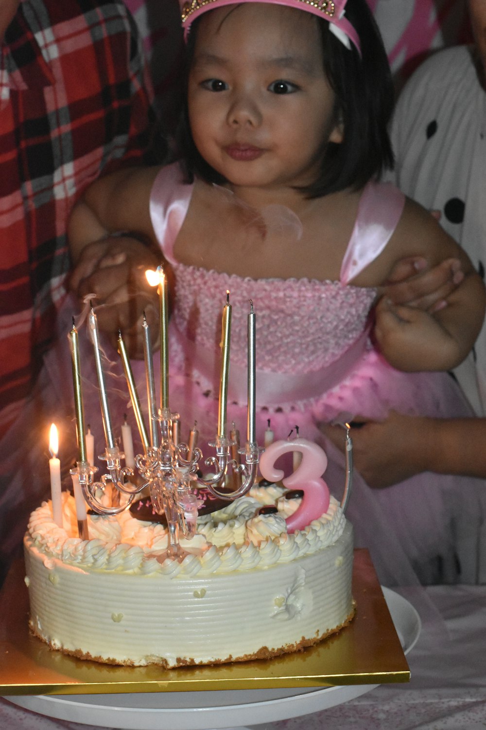 a little girl standing in front of a cake with candles