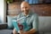 A smiling man holding the book 'Trust No One' in a cozy reading nook.