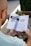 A person is holding an open book titled 'Part One: How Does Storytelling Work?' The book discusses the importance of stories. The setting includes a wooden table, plants, and a blurred outdoor background.