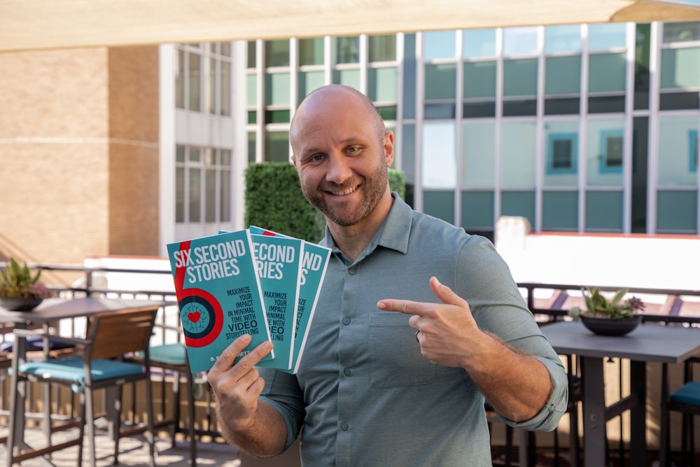 a man holding up a book in front of a building