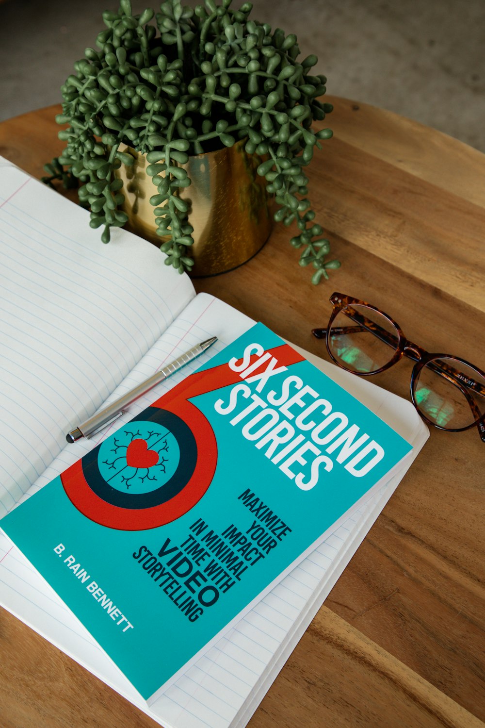 a notebook with a pen and glasses on a table