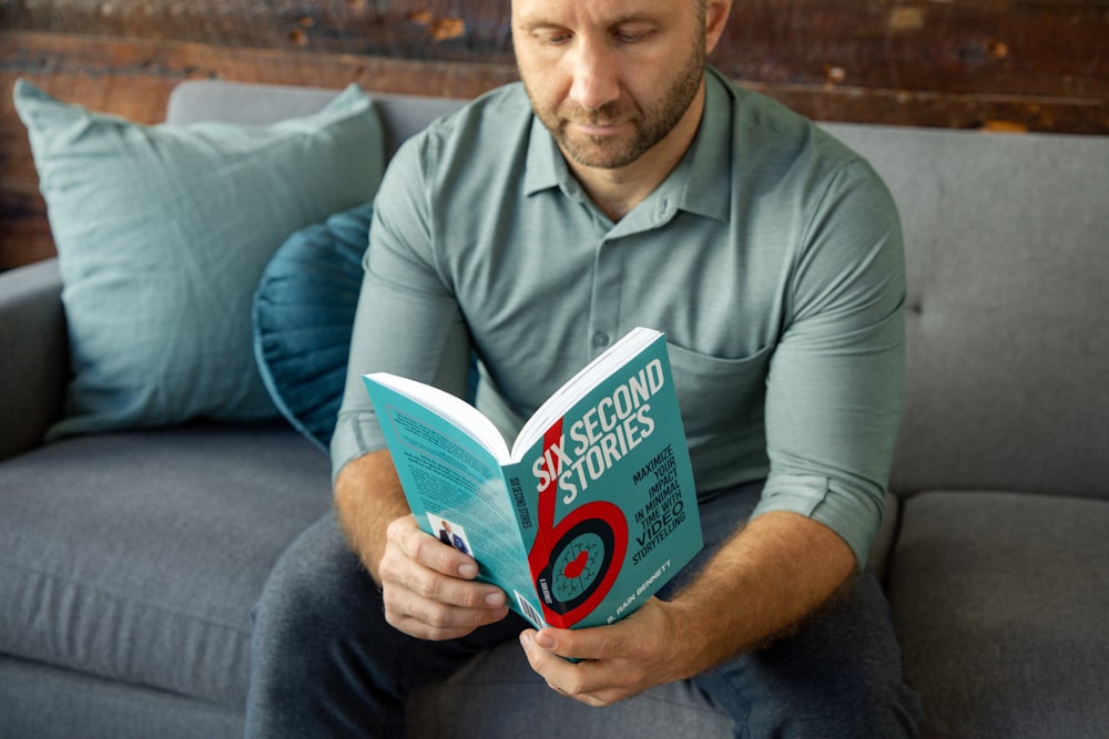 a man sitting on a couch reading a book