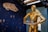 A gold humanoid robot is holding a tray with several stacked items. The wall in the background displays a dark blue space-themed mural with a large white spaceship and scattered star-like dots.