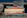 A stack of books is placed on a table with various titles visible, ranging from business negotiation and success strategies to creativity and philanthropy. The books are neatly arranged and the background includes another stack of books slightly out of focus.