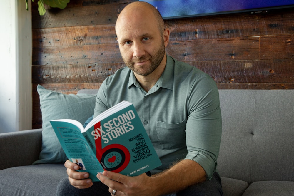 a man sitting on a couch holding a book