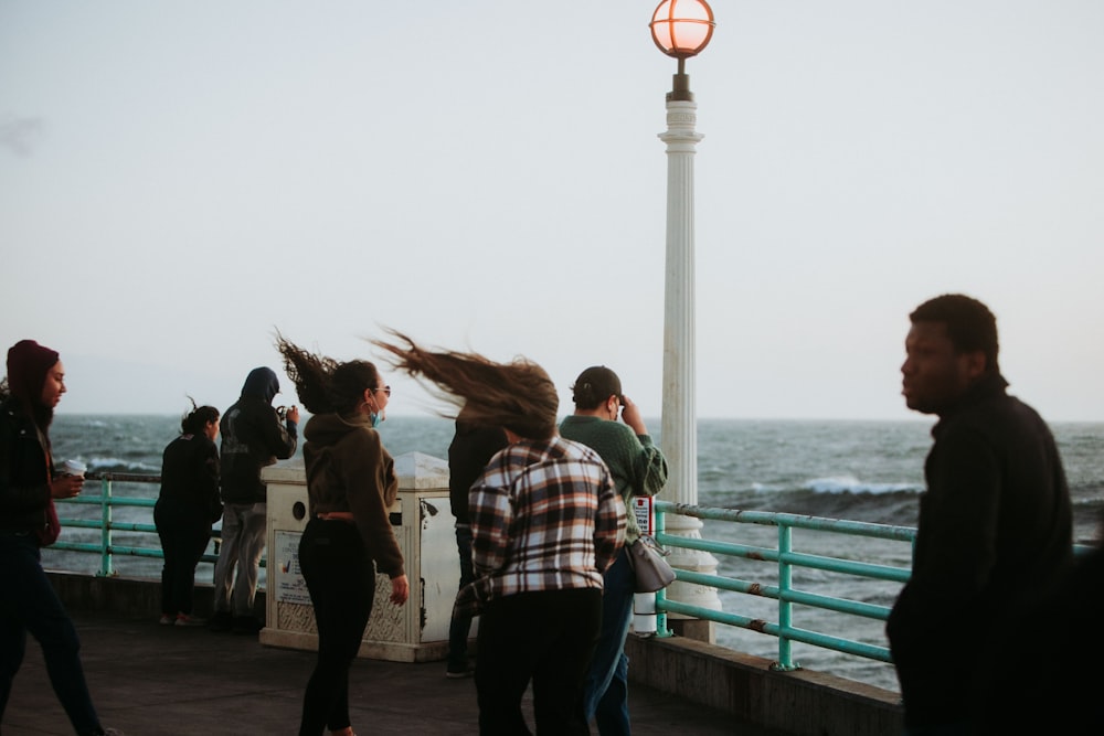 a group of people standing on a pier next to the ocean