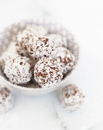 a bowl filled with chocolate covered donuts on top of a table