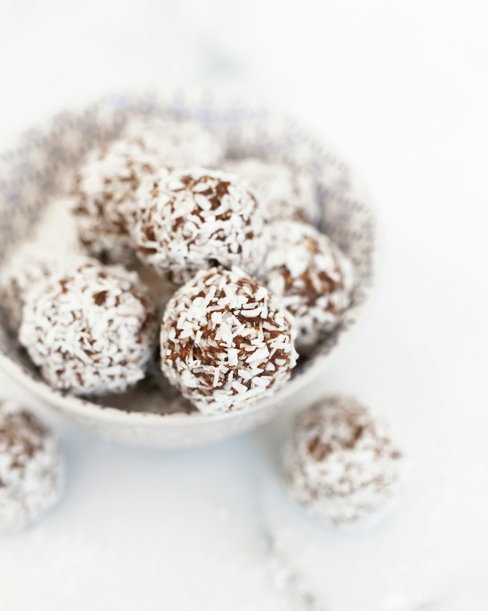 a bowl filled with chocolate covered donuts on top of a table