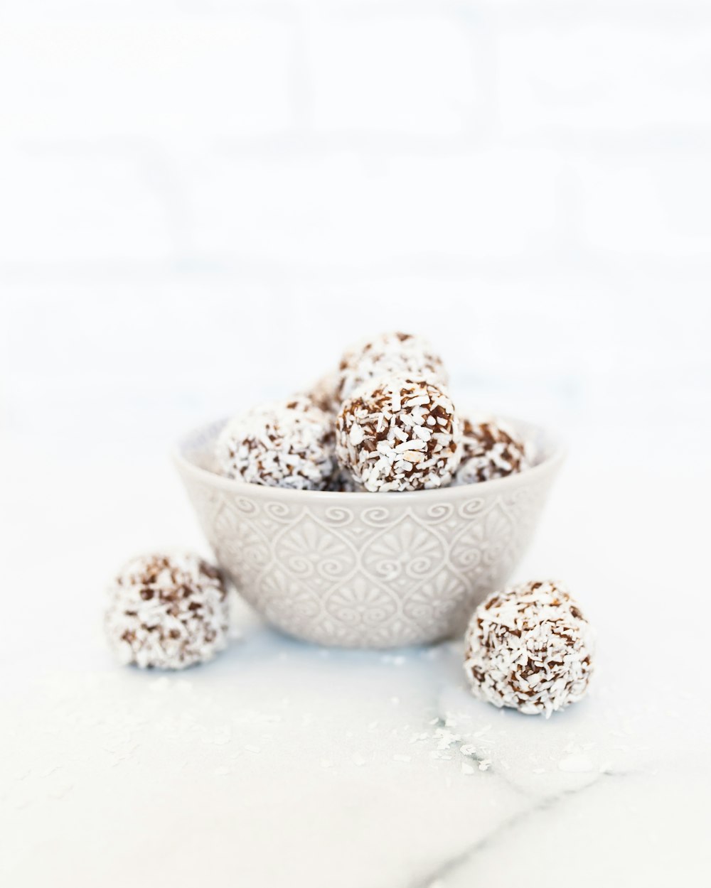 a white bowl filled with chocolate covered donuts