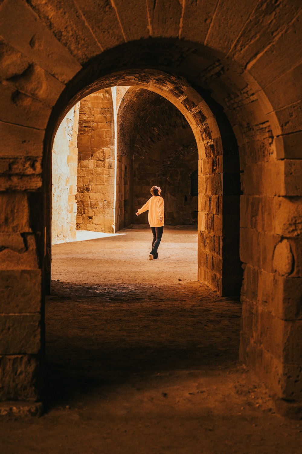 a man walking through a tunnel in a stone building