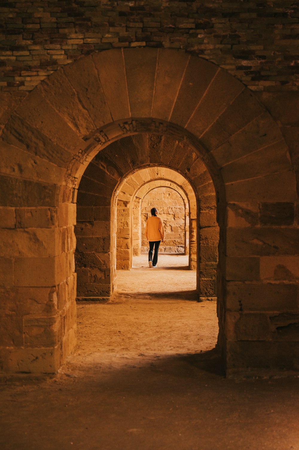 a man walking through a tunnel in a stone building