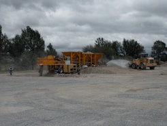 Close-up of heavy machinery working on a large civil engineering project with dust in air.