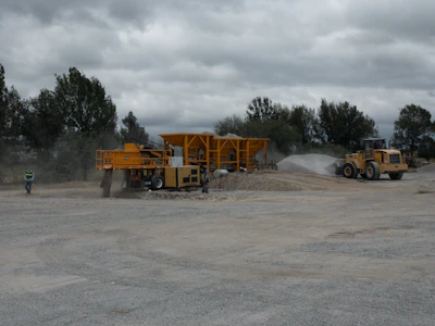 Heavy machinery in action on a dusty construction site under a dark yellow sky.