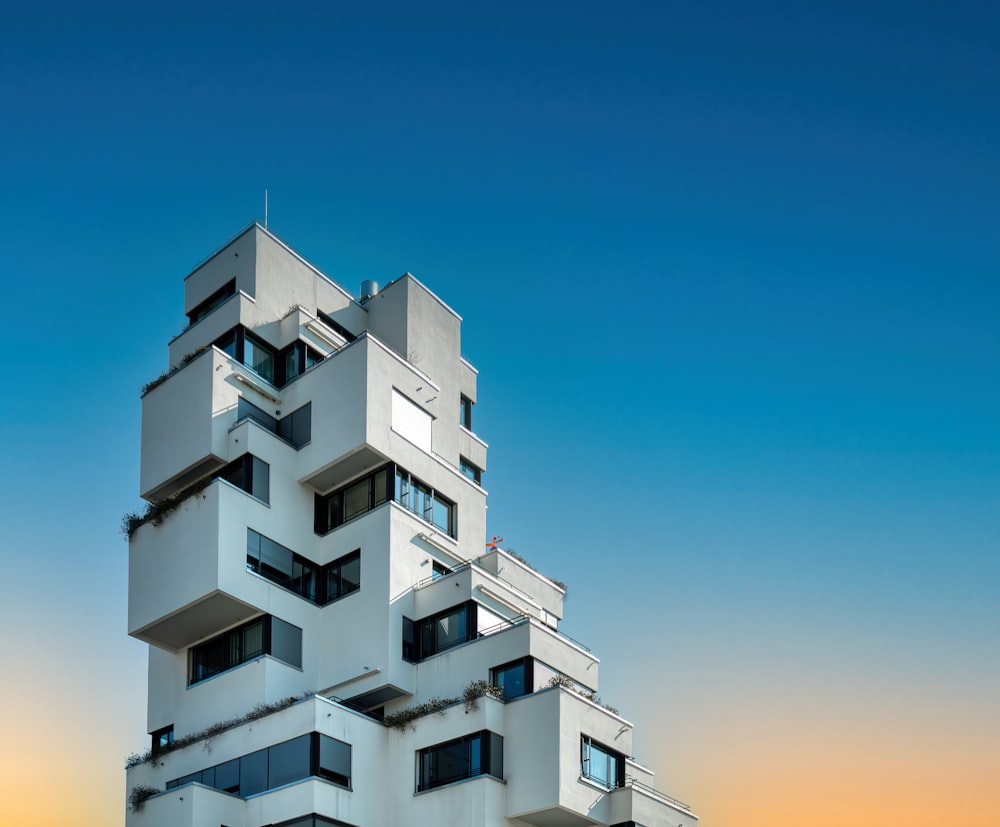 a tall white building with balconies on top of it