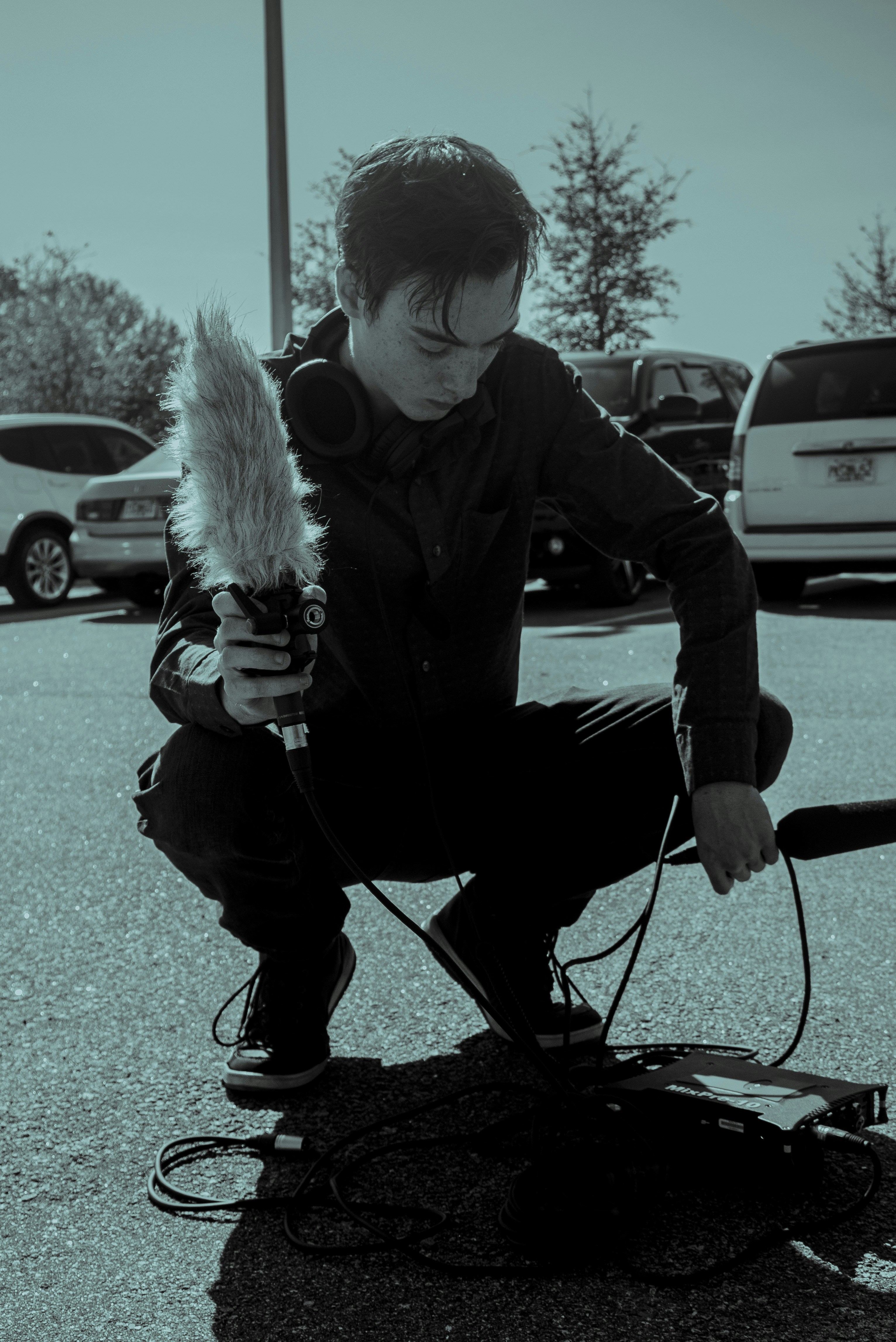 a man kneeling down holding a device with a feather on it