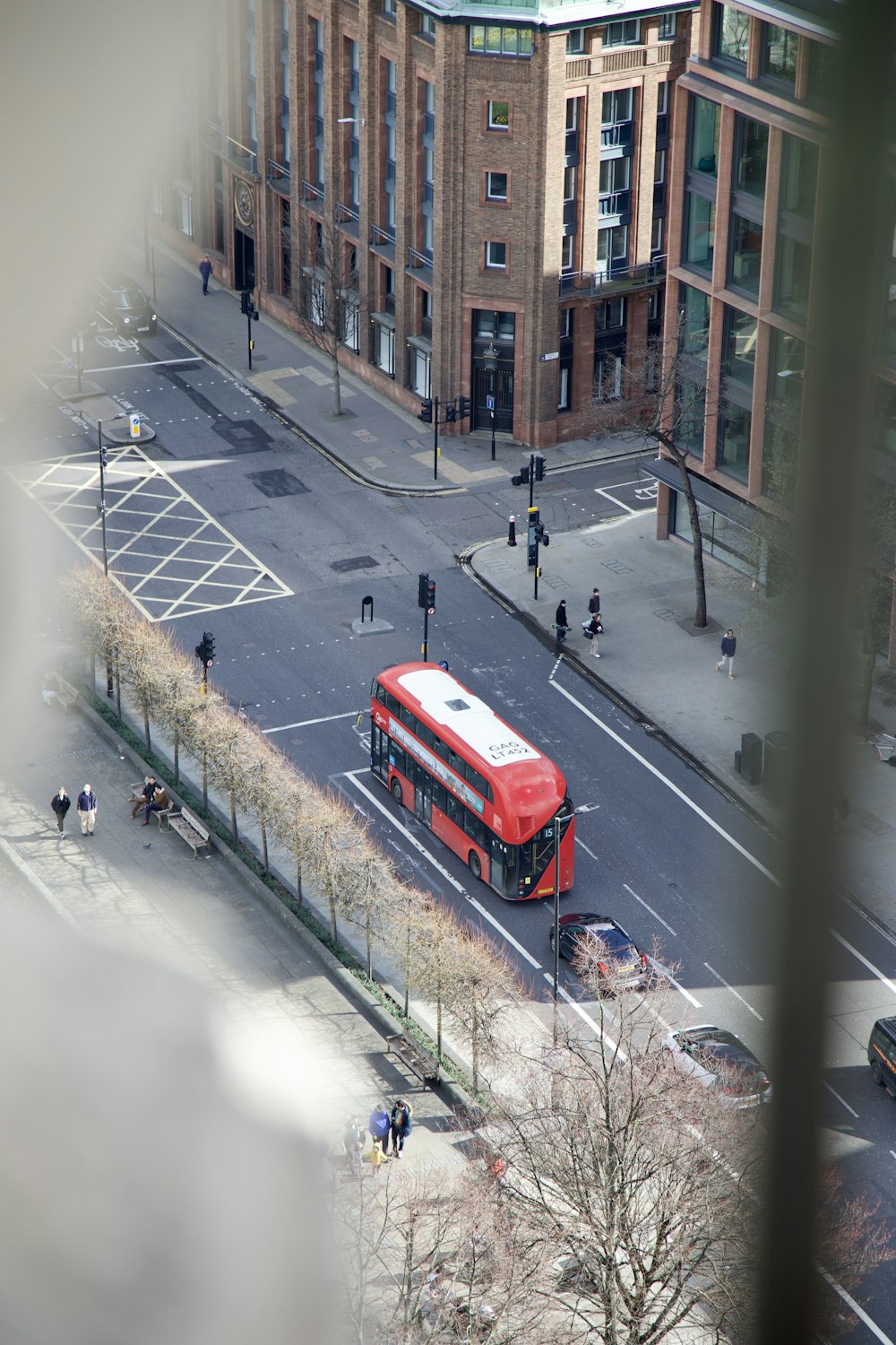 Un autobús rojo conduciendo por una calle junto a edificios altos