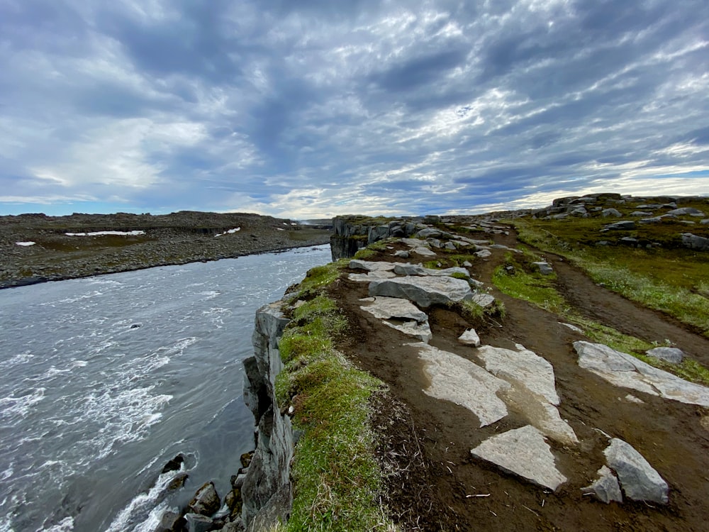 a body of water surrounded by rocks and grass