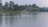 Woman casting a fishing line from a kayak on a calm lake surrounded by lush greenery.