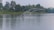 Woman casting a fishing line from a kayak on a calm lake surrounded by lush greenery.
