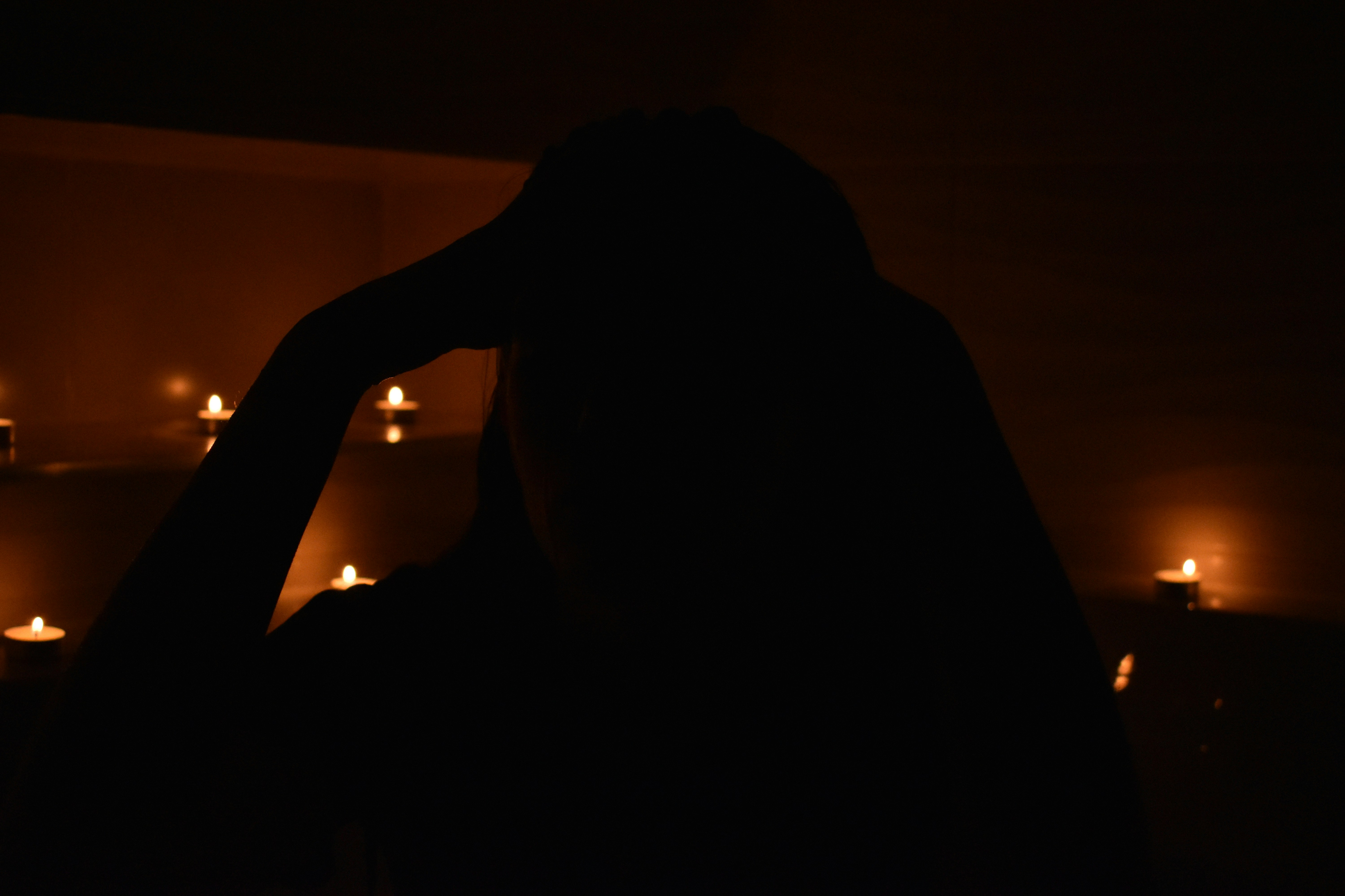 Silhouette of a person with candles in the dark
