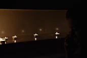 A shadowy figure narrating a story to an attentive group around a candlelit table.