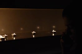 A shadowy figure narrating a story to an attentive group around a candlelit table.