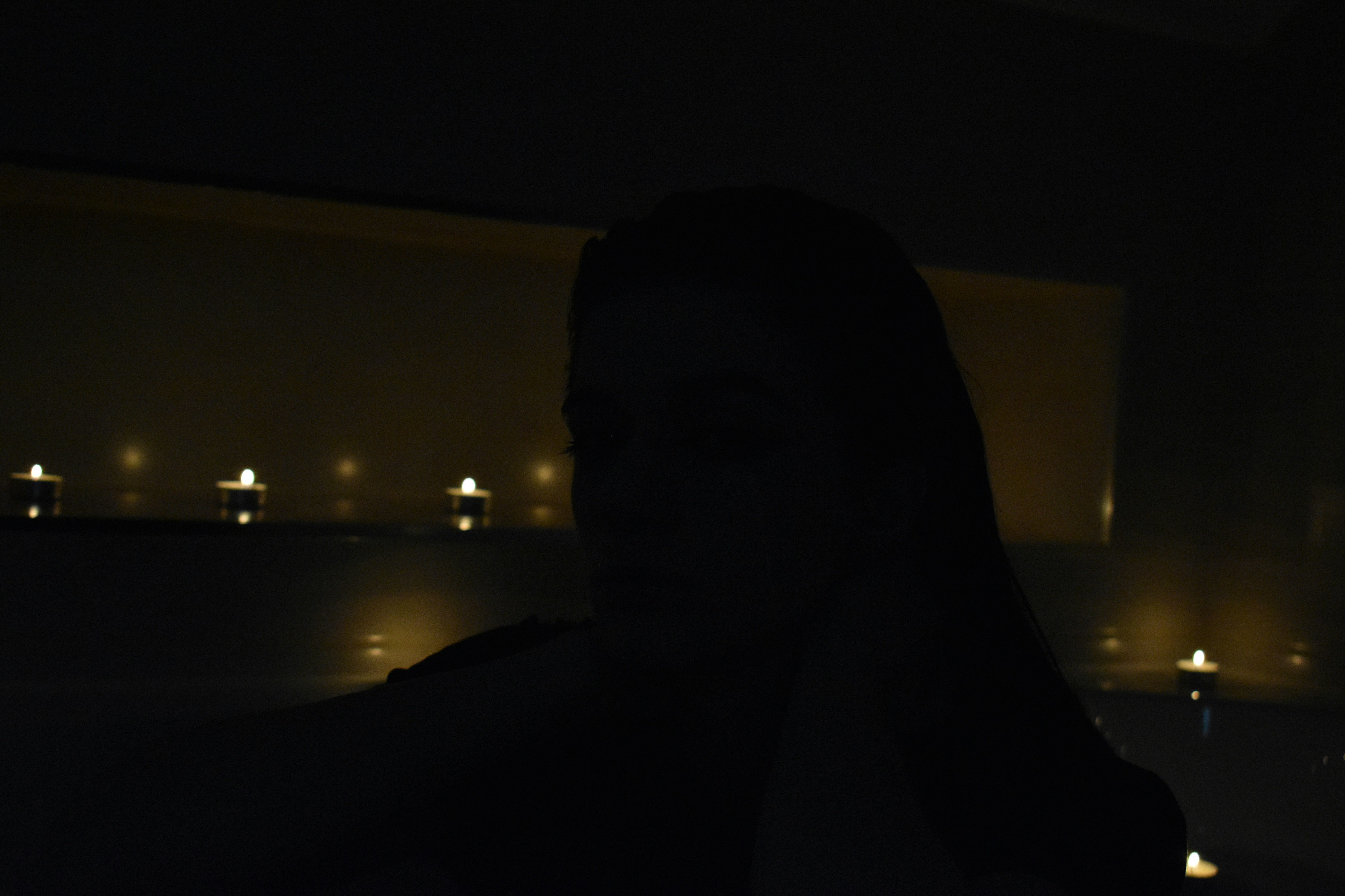 Silhouette of a person with candles in the background.