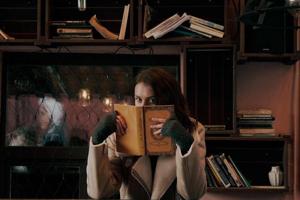 a woman reading a book in front of a bookshelf