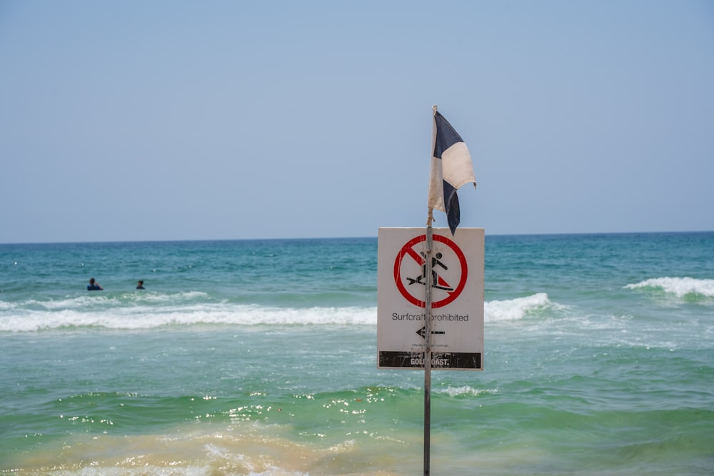 a sign on a pole in front of a body of water