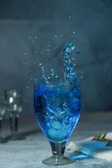 a blue liquid splashing into a glass of water