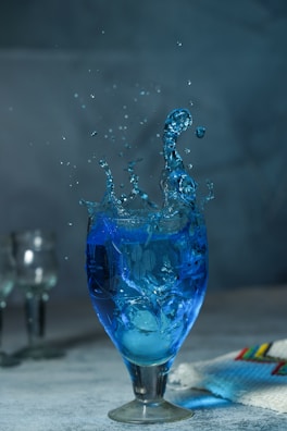 a blue liquid splashing into a glass of water