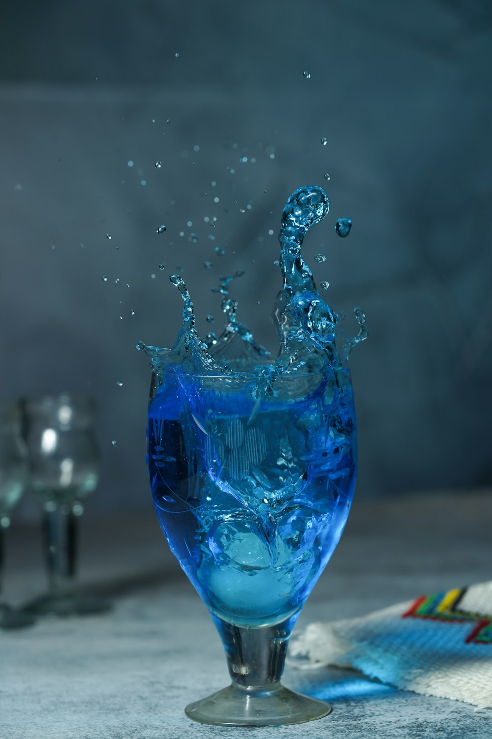 a blue liquid splashing into a glass of water
