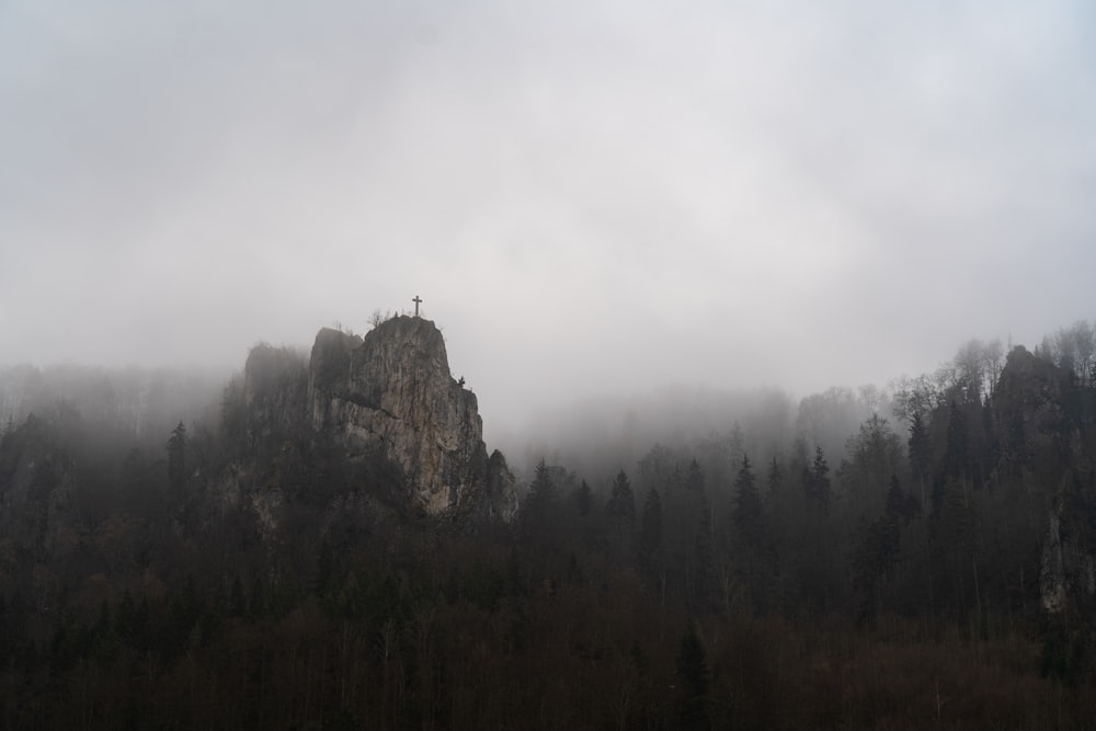 Una montagna coperta di nebbia con una croce in cima