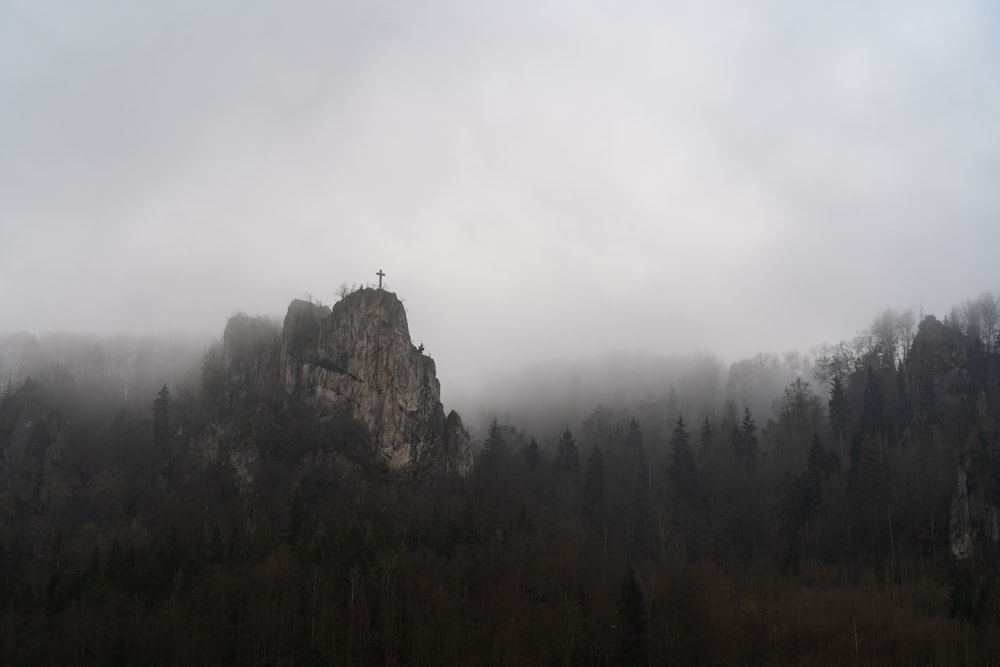 a mountain covered in fog with a cross on top of it