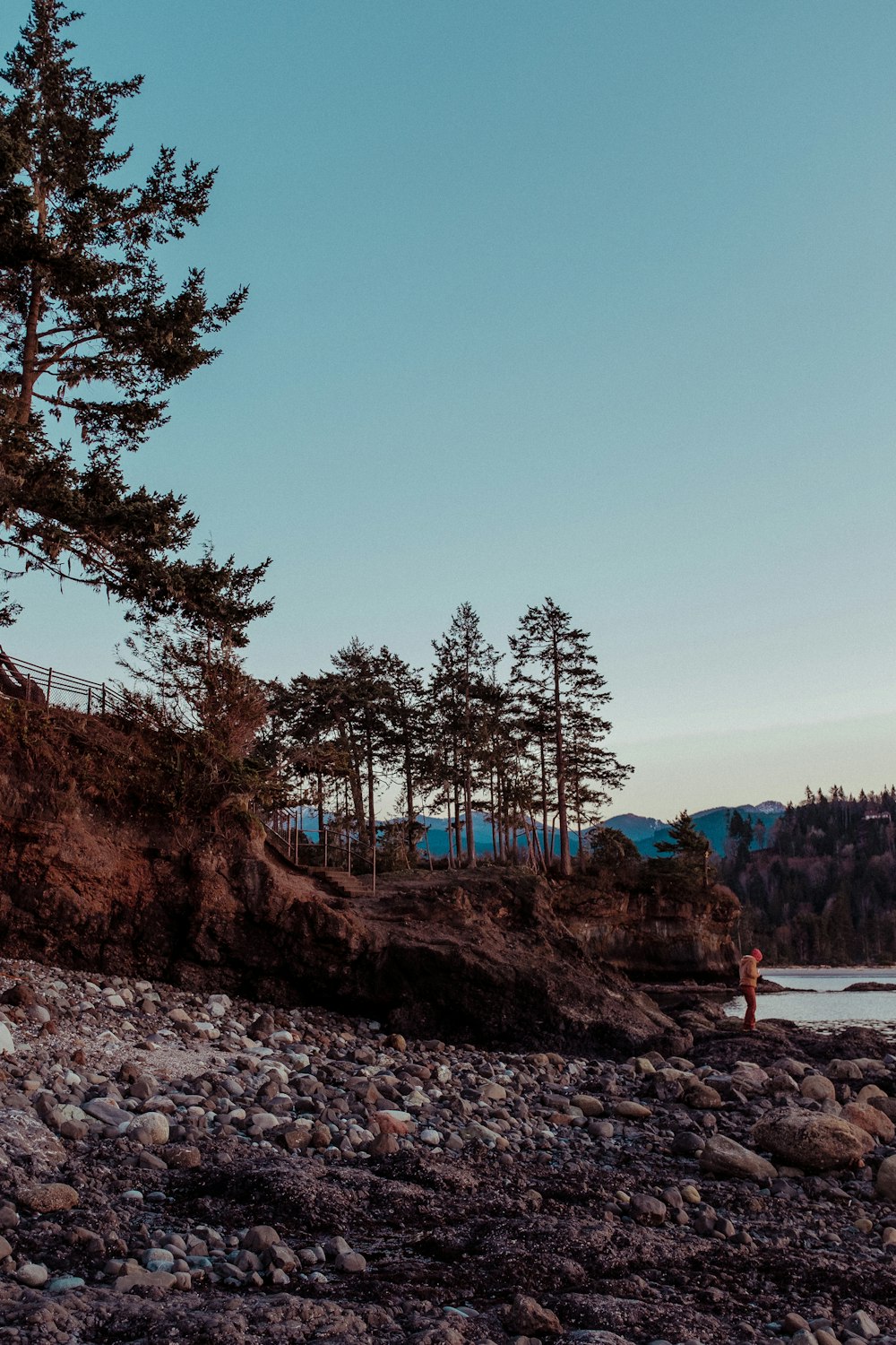 a person standing on a rocky beach next to a body of water