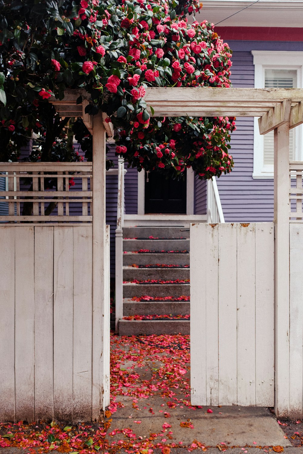 a white gate with flowers on it next to a house
