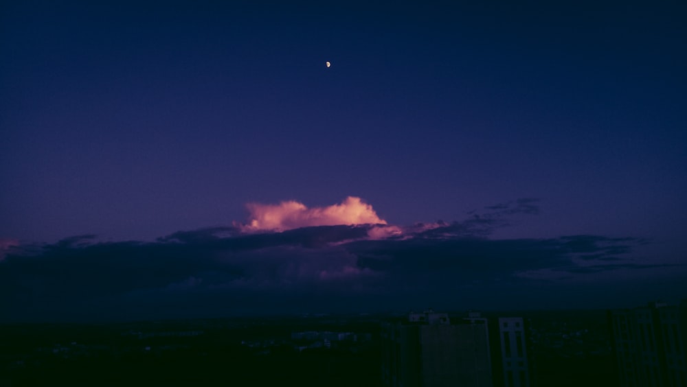 a cloud in the sky with a moon in the distance