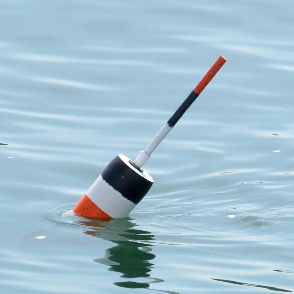 an orange and white pole sticking out of the water